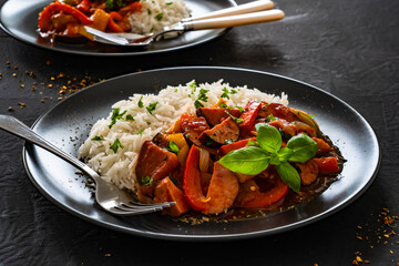 Polish lecho with white rice - bell pepper tomato stew with sausages on black table