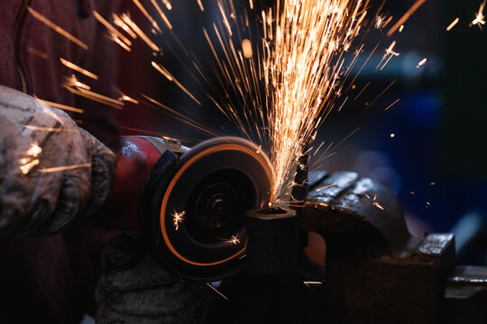 Craftsman sawing metal with disk grinder saw in workshop