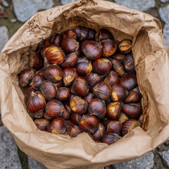 Obraz premium Overhead shot of roasted chestnuts in paper bag, street food style