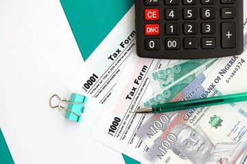 Nigerian naira money bills and calculator with tax form on flag. Taxation and accounting concept