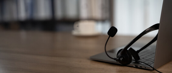Professional office mood with headset resting on laptop, natural light and negative space for...