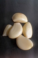 Fresh garlic bulbs and cloves on a stainless steel cutting board, showcasing their natural texture and culinary freshness, ideal for cooking and healthy food concepts.