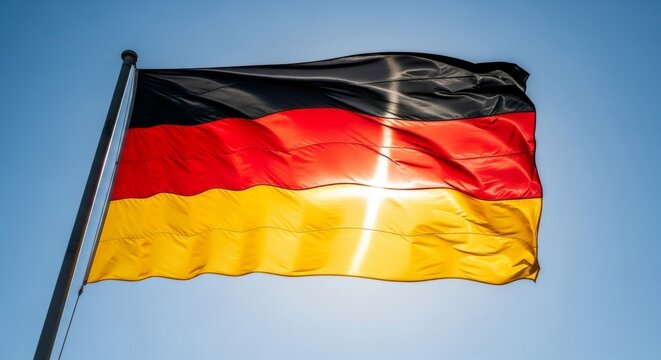 German flag waving against clear blue sky with sunlight reflection
