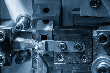 Close up operation of the wire coil spring making machine in the blue tone.