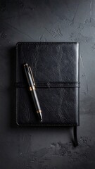 Black leather notebook and pen on dark textured surface