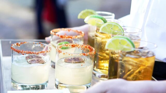 Slow motion of Spicy margarita and Long Island iced tea on serving treys during the day at a wedding reception