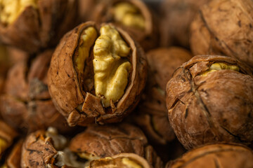 Walnut peeled kernels and whole walnuts on rustic wooden background. Healthy nuts food. Macro. Cracked shells