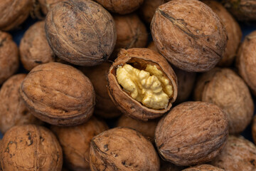 Walnut peeled kernels and whole walnuts on rustic wooden background. Healthy nuts food. Macro. Cracked shells