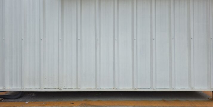 White metal sheet wall of a street food stall. Glossy white metal sheet panels. White Corrugated metal texture surface of fence wall. White painted steel wall texture image.