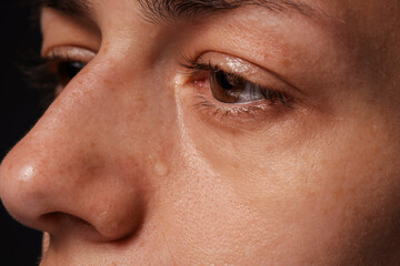 Fototapeta premium Sad woman crying on black background, closeup