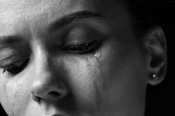Obraz premium Sad woman crying on dark background, closeup. Black and white effect