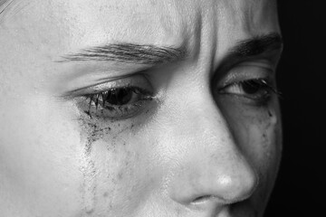 Naklejka premium Sad woman crying on dark background, closeup. Black and white effect