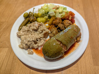 Homemade Middle Eastern Meal with Stuffed Zucchini, Tahini, and Pickles on Wooden Table