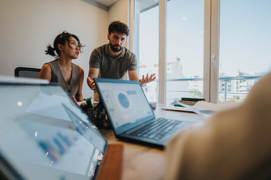 Couple seeking financial guidance from a bank advisor. Discussion involves charts and data analysis displayed on laptops, reflecting advice and decision-making focused on loans and financial services.