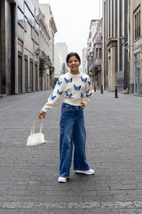 She is wearing blue jeans and has her arms crossed