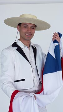 Happy chilean man in traditional huaso clothing holding the flag of chile on a white background