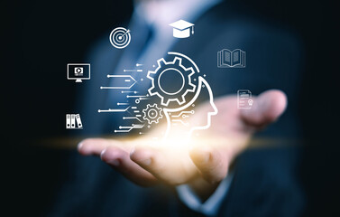 Businessman holding glowing human head with gears and education icons, symbolizing knowledge management, learning innovation, digital training, and business intelligence development. smart learning AI