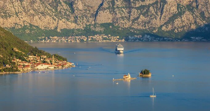 Sunset over Kotor Bay with Perast town, cruise ship, and the islands of Our Lady of the Rocks and St. George surrounded by calm sea and majestic mountains.