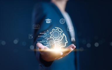 Businessman holding a glowing brain and gear icon, symbolizing learning, innovation, knowledge, artificial intelligence, skill development, and modern education technology concept.