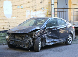 A broken-down black car stands near a yellow house wall, Narodnaya Street, Saint Petersburg, Russia, October 07, 2025