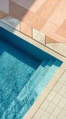 Obraz premium Ripresa dall'alto di un angolo di una piscina circondata da superfici pavimentate in materiali beige.