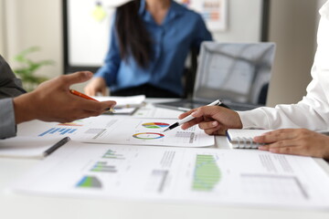 Business people analyzing financial charts and graphs at meeting, discussing company performance and making strategic decisions based on the presented data.
