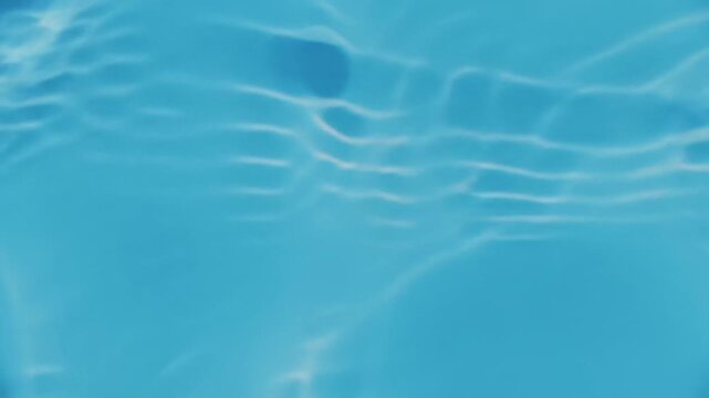 Overhead ecu video of pristine, light blue water with gentle micro-ripples and natural sunlight reflections. abstract fluid texture evoking profound tranquility, clarity, and coolness