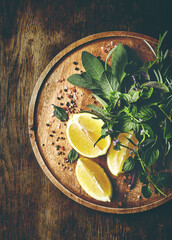 Fresh herbs and lemons on wooden tray. Top view. Copy space