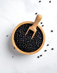 Wooden bowl filled with black beans, a wooden scoop nestled within