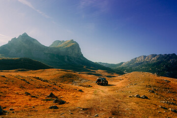 Off-road van parked in a golden mountain valley under a clear blue sky in Durmitor National Park, Montenegro © Maria Ivanova
