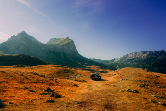 Off-road van parked in a golden mountain valley under a clear blue sky in Durmitor National Park, Montenegro