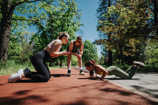 A group of people engages in an intense fitness session outdoors, emphasizing teamwork and physical strength under the vibrant sunlight and surrounded by lush greenery.