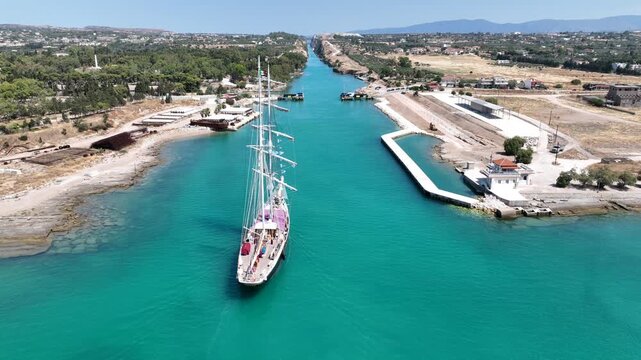 Aerial drone cinematic video of classic sailing boat crossing narrow Corinth canal of Isthmus from West submersible bridge and narrow opening of Corinthian gulf to Saronic gulf, Loutraki, Greece