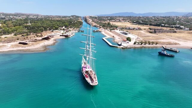 Aerial drone cinematic video of classic sailing boat crossing narrow Corinth canal of Isthmus from West submersible bridge and narrow opening of Corinthian gulf to Saronic gulf, Loutraki, Greece
