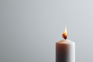 A solitary white candle burns brightly against a neutral background, embodying concepts like hope, remembrance, peace, and reflection. Ideal for contemplative or spiritual themes.