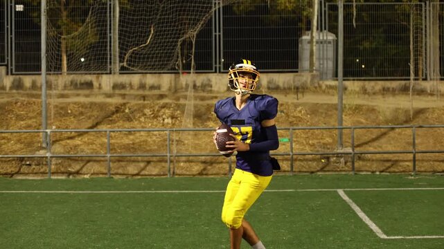American football quarterback throwing a pass during a night game