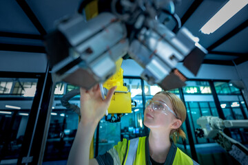 A robotics engineer uses a tablet to program a robot with a machine vision system, while her colleague calibrates the end-of-arm tooling on another unit in a system integration lab.