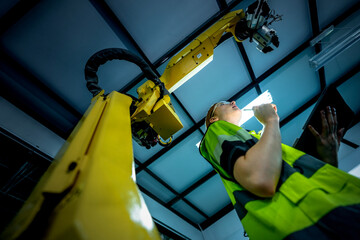 In an Industry 4.0 smart factory, an engineer uses a tablet to run an AI machine vision algorithm on a collaborative robot cobot, optimizing production via a real time digital twin.