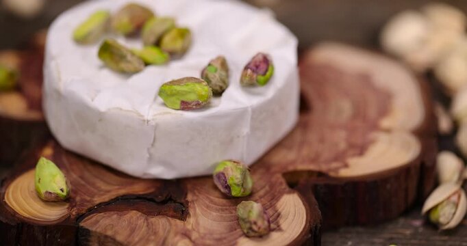 unshelled pistachios are on the table along with whole cheese in white mold, delicious white soft cheese in mold and a large number of salted pistachios