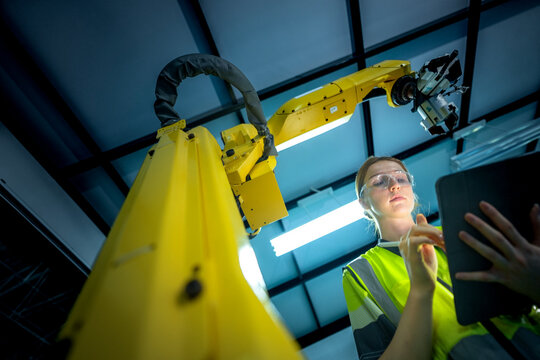 In an Industry 4.0 smart factory, an engineer uses a tablet to run an AI machine vision algorithm on a collaborative robot cobot, optimizing production via a real time digital twin. - Powered by Adobe