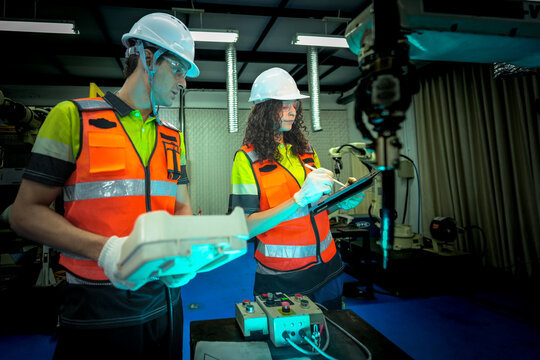 In a smart factory, an engineer uses an augmented reality tablet to guide her partner through a complex repair, overlaying digital instructions on the robot after an AI alert.