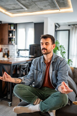 Fototapeta premium Man practicing mindful meditation in living room at home