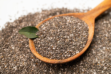 Chia seeds in wooden spoon on white background flat lay top view. Food background, healthy eating concept, superfood. Dry organic chia seeds rich in omega-3, protein, vitamins and minerals