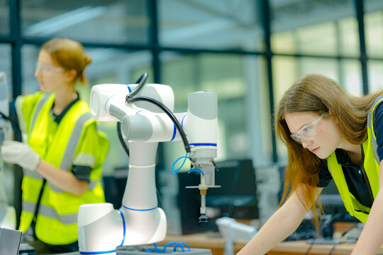 In a smart factory, engineers use augmented reality on a laptop to overlay a digital twin onto a robotic arm, performing AI-guided predictive maintenance with pinpoint accuracy.