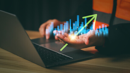 Businessman analyzing financial growth on laptop with glowing bar chart and upward arrow symbolizing success, digital data analytics, and financial performance improvement in modern business.