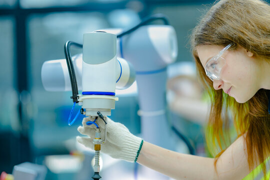 A robotics engineer uses a tablet to program a robot with a machine vision system, while her colleague calibrates the end-of-arm tooling on another unit in a system integration lab.