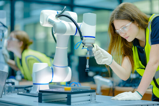 Two technicians program a collaborative robot cobot for a precise pick-and-place task, working safely alongside the machine to optimize its movements and end-effector grip.