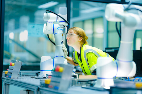 In a smart factory, engineers use augmented reality on a laptop to overlay a digital twin onto a robotic arm, performing AI-guided predictive maintenance with pinpoint accuracy.