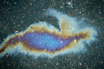 Oil slick on pavement forming colorful iridescent patterns, symbolizing pollution and environmental impact