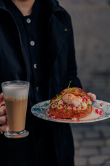 A girl in dark clothes holds a plate of food in her hands